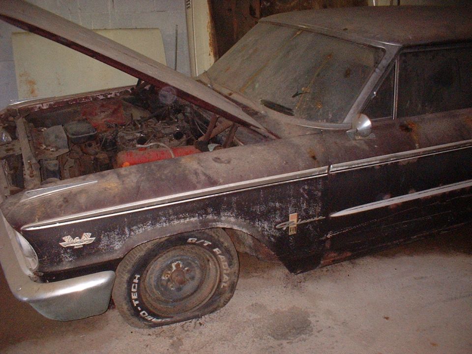 Rusty 1963 Ford Galaxie with hood open, flat tire, and chrome trim