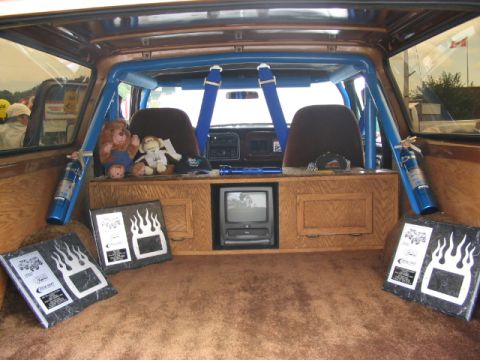 1986 Ford Bronco - Custom interior of an SUV a roll cage, entertainment system, and plush carpeting.