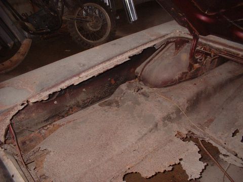1963 Ford Galaxie - Severe rust damage on the trunk floor of a car, with a motorcycle visible behind it.