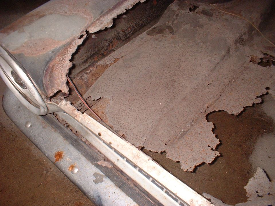 Close-up of heavily rusted car floor pan with missing metal and some water damage