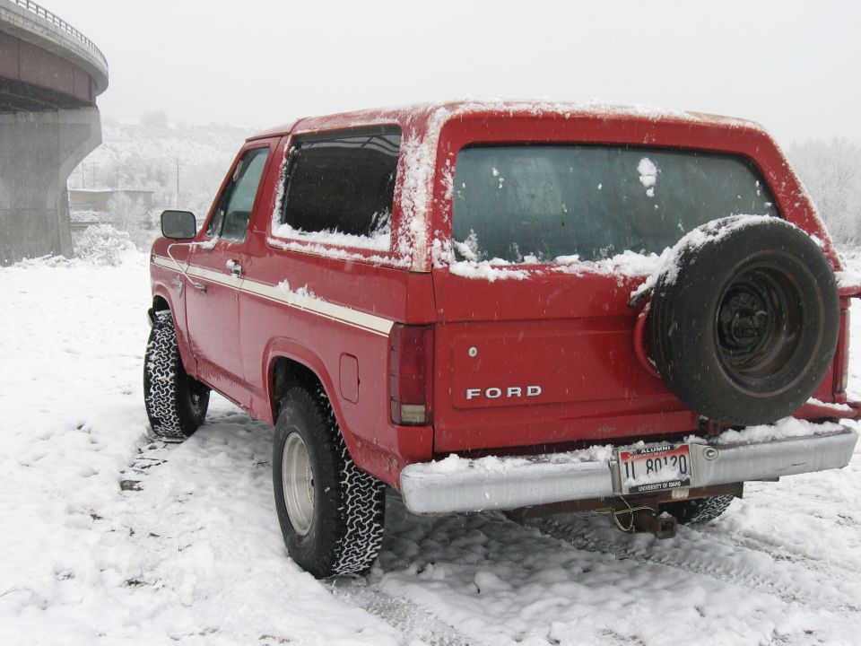 Red 1981 Ford Bronco rear view in snow with spare tire mounted