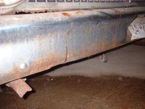 1963 Ford Galaxie - This close-up shows significant rust and damage on a vehicle's lower body panel, with a partial license plate in view.