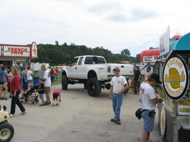 Lifted white pickup truck at an outdoor event with food stands