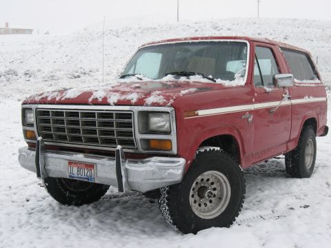 1981 Ford Bronco - A red 1981 Ford Bronco sits in the snow, showing its front 3/4 profile.