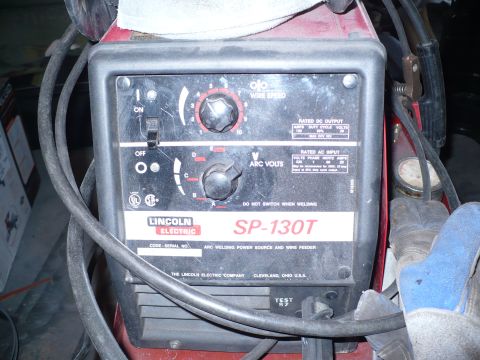 1979 Ford Bronco - Close-up of the front control panel of a red Lincoln Electric SP-130T MIG welder, showing the ON/OFF switch, numbered wire-speed dial and l…