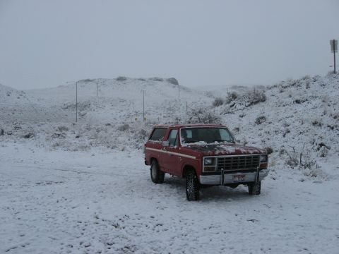 1981 Ford Bronco - A red 1981 Ford Bronco sits in a snowy landscape, its tires covered in snow.
