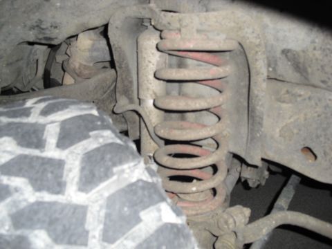 1992 Ford Bronco - Close-up view of a vehicle's suspension system, including a tire and coil spring.