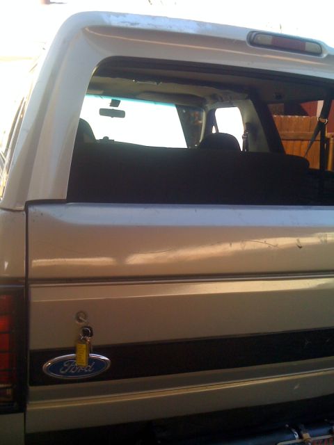1992 Ford Bronco - The rear of a 1992 Ford Bronco is visible, showing the Ford emblem and a key in the tailgate lock.