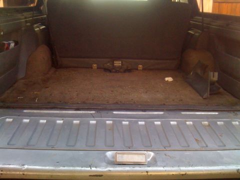 1992 Ford Bronco - The cargo area of the vehicle appears dirty and shows signs of wear, with the rear seats folded down.