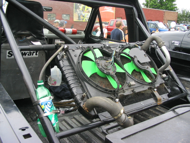 Truck interior with roll cage, dual green fans, and radiator. Sprite bottle attached to a pipe