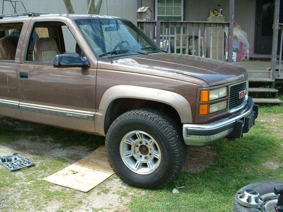 Brown and tan GMC 2500 Suburban on grass with new aluminum wheel and all-terrain tire