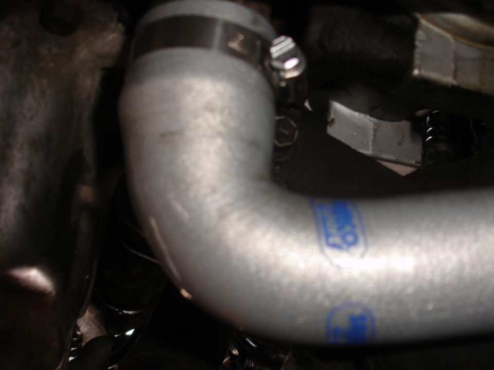 Close-up of a silver engine hose with blue lettering and a clamp