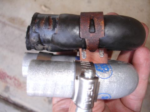 1992 Ford Taurus - Comparison of a worn black hose and a new silver hose, both secured with metal clamps.