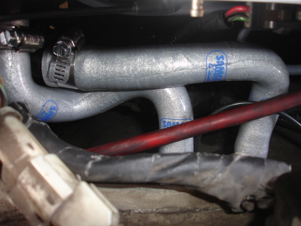 Close-up of silver engine hoses with blue "Samco" logos and metal clamps