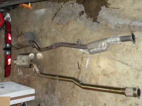 1998 Subaru Legacy - Stock and aftermarket exhaust systems are shown side-by-side on a garage floor.