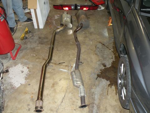 1998 Subaru Legacy - Two exhaust systems are shown on a concrete floor, one appears newer than the other.