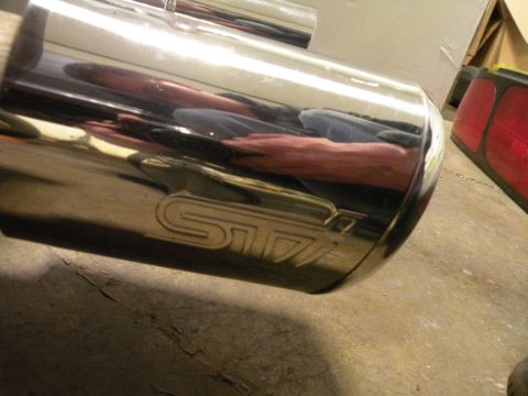 1998 Subaru Legacy - Close-up of an STI exhaust tip, showing the stamped logo and reflections.