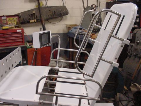 1978 Ford F-250 - A white seat with chrome rails is seen in a workshop setting, with tools and equipment in the background.