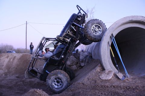 1989 Ford Bronco - A custom off-road buggy is precariously balanced while attempting to navigate a large concrete pipe obstacle.