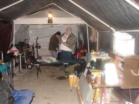 1973 Ford Ranchero - Two men stand inside a cluttered tent filled with camping equipment and supplies.
