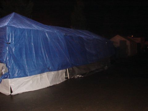 1973 Ford Ranchero - A vehicle is covered by a blue tarp and white skirting, seen at night.