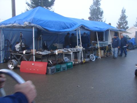1973 Ford Ranchero - A red car trunk lid is displayed for sale at an outdoor market under a blue tent.