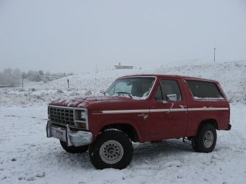 1981 Ford Bronco - A red 1981 Ford Bronco sits in a snowy landscape, viewed from the front three-quarter angle.