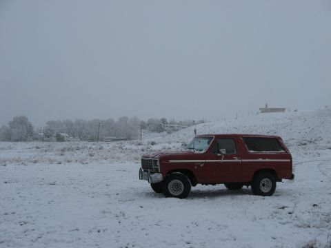 1981 Ford Bronco - A red Ford Bronco sits in a snow-covered field under an overcast sky.