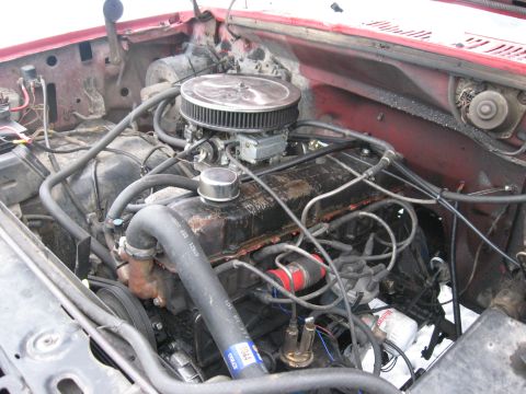 1981 Ford Bronco - Engine bay view of an older Ford with a V8 engine topped by a chrome round air cleaner and a four-barrel carburetor. The valve cover and bl…