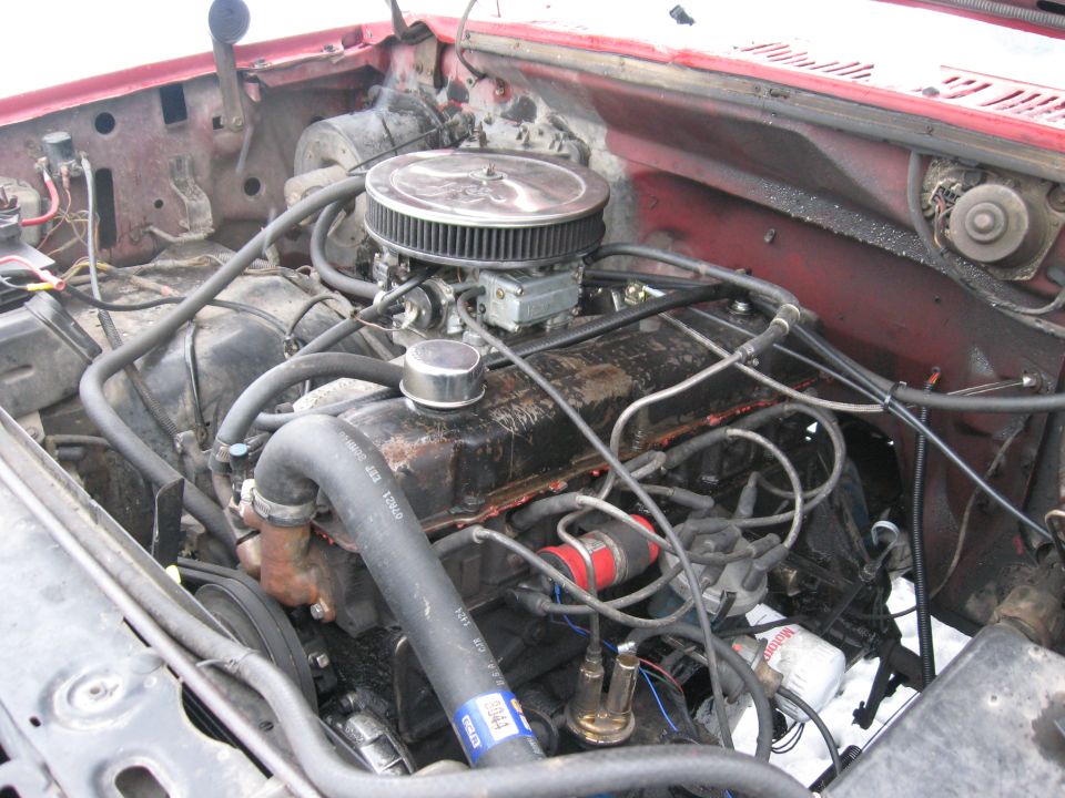 Grimy V8 engine bay with chrome air cleaner and red inner fenders