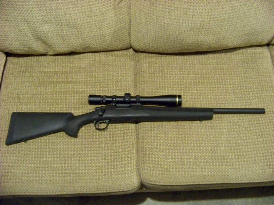 Rifle with a scope mounted on top, resting on a textured fabric surface
