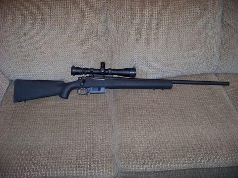 1995 Mercury Grand Marquis - A rifle with a scope is resting on a textured couch.