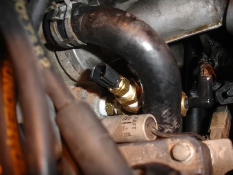 1992 Ford Taurus - Close-up of an engine coolant temperature sensor installation, showing brass fitting and electrical connector.