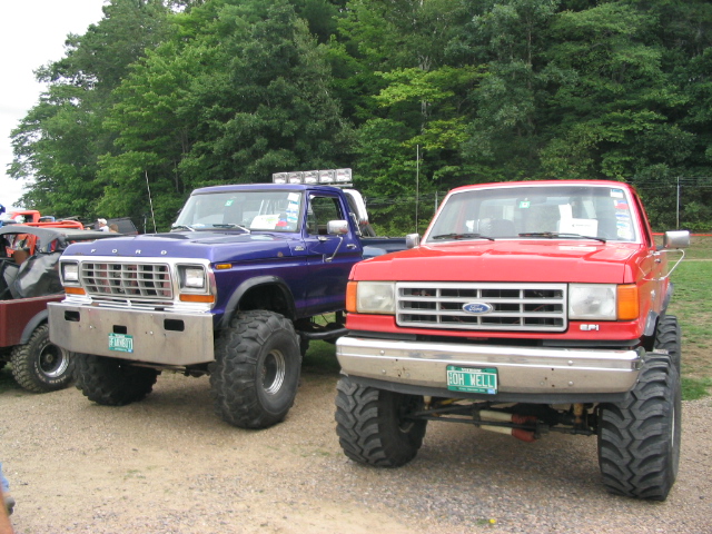 Blue 1980s Ford pickup and red 1980s Ford pickup, both lifted