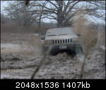 1979 Ford Bronco - A Hummer H2 navigates a muddy terrain, its front grille clearly visible.