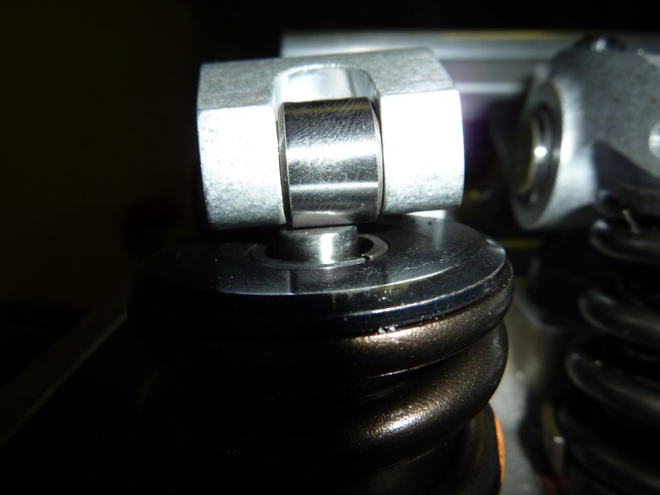 Close-up of a roller rocker arm assembly on a valve spring