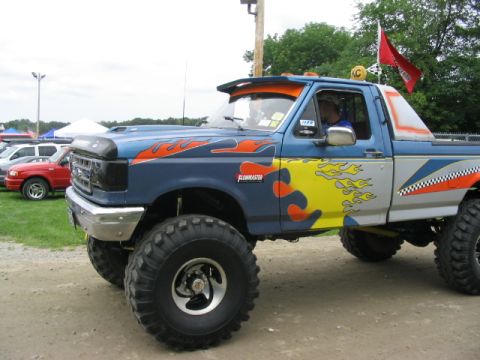 1986 Ford Bronco - This modified pickup truck features custom flame graphics and oversized tires, suggesting it's built for off-road performance.