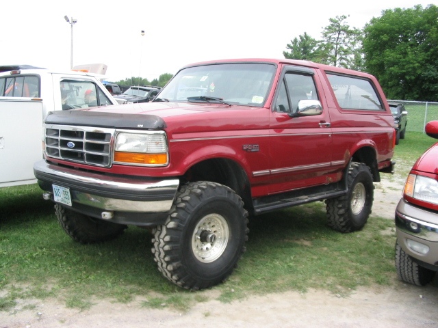 Red 1986 Ford Bronco with lifted suspension and large tires