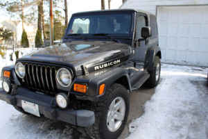 1996 Ford Bronco - This Jeep Wrangler Rubicon is parked outside a garage in snowy conditions.