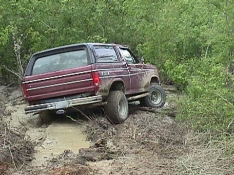 1984 Ford Bronco - This maroon Ford Bronco appears to be from the early 1980s, judging by its body style, as it struggles through a muddy off-road path.