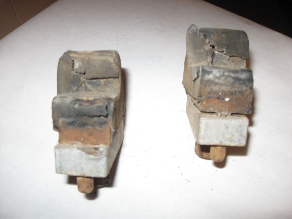 two old, damaged rubber and metal components with bolts