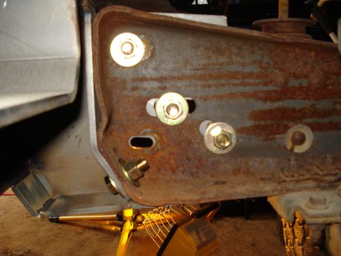 1991 Ford Bronco - Close-up view of a rusted metal bracket with several bolts, supported by a yellow jack stand.