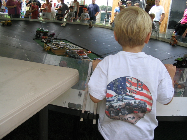 Toy trucks race on a track as a child watches