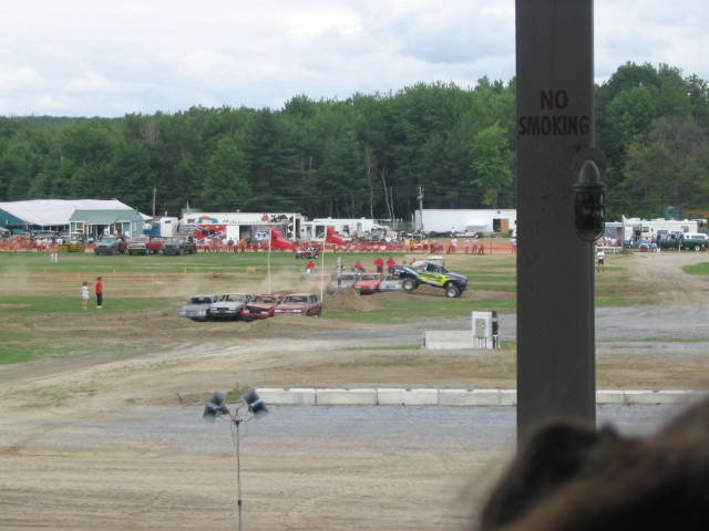 Monster truck jumps over wrecked cars at an outdoor event