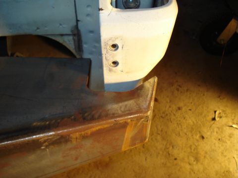 1991 Ford Bronco - Close-up view of a rusted metal bumper and a white fender, showing construction details.