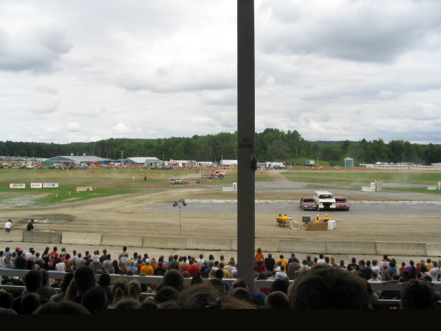 Crowd watching event at outdoor venue with buildings and trees in background