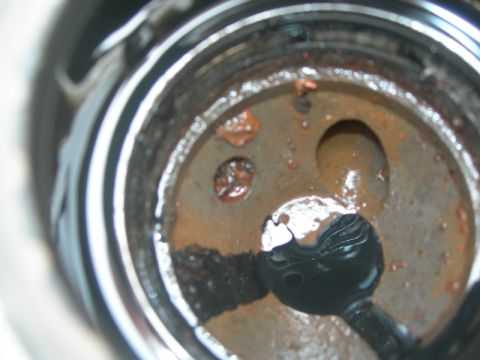 1984 Ford Bronco - A close-up view of a rusty engine component, showing signs of wear and sludge accumulation.