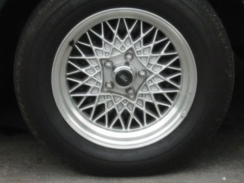 1998 Ford Crown Victoria - A silver wire-spoke wheel with a Ford logo in the center is shown on a tire.