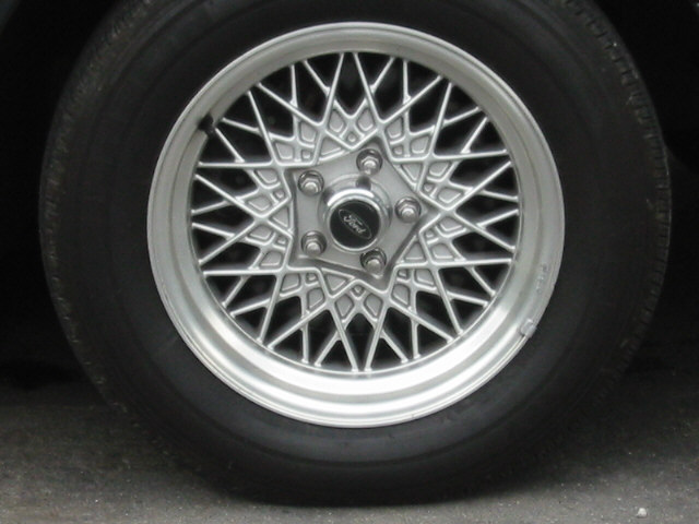 Close-up of a silver Ford wire-spoke wheel and tire
