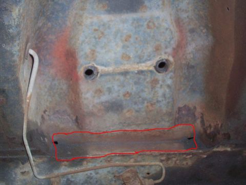 1969 Ford Torino - Close-up of a heavily rusted car frame section, showing structural damage and two bolt holes.